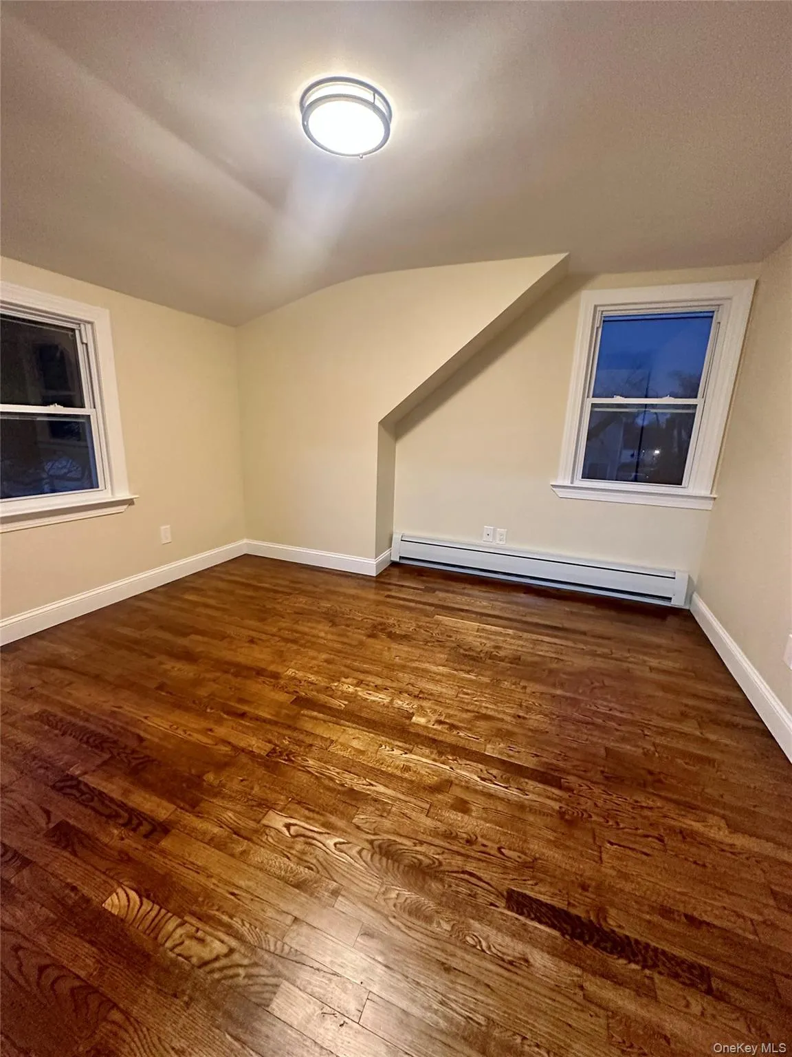 Bonus room with lofted ceiling, wood finished floors, a baseboard heating unit, and baseboards Bonus room with lofted ceiling, wood finished floors, a baseboard heating unit, and baseboards