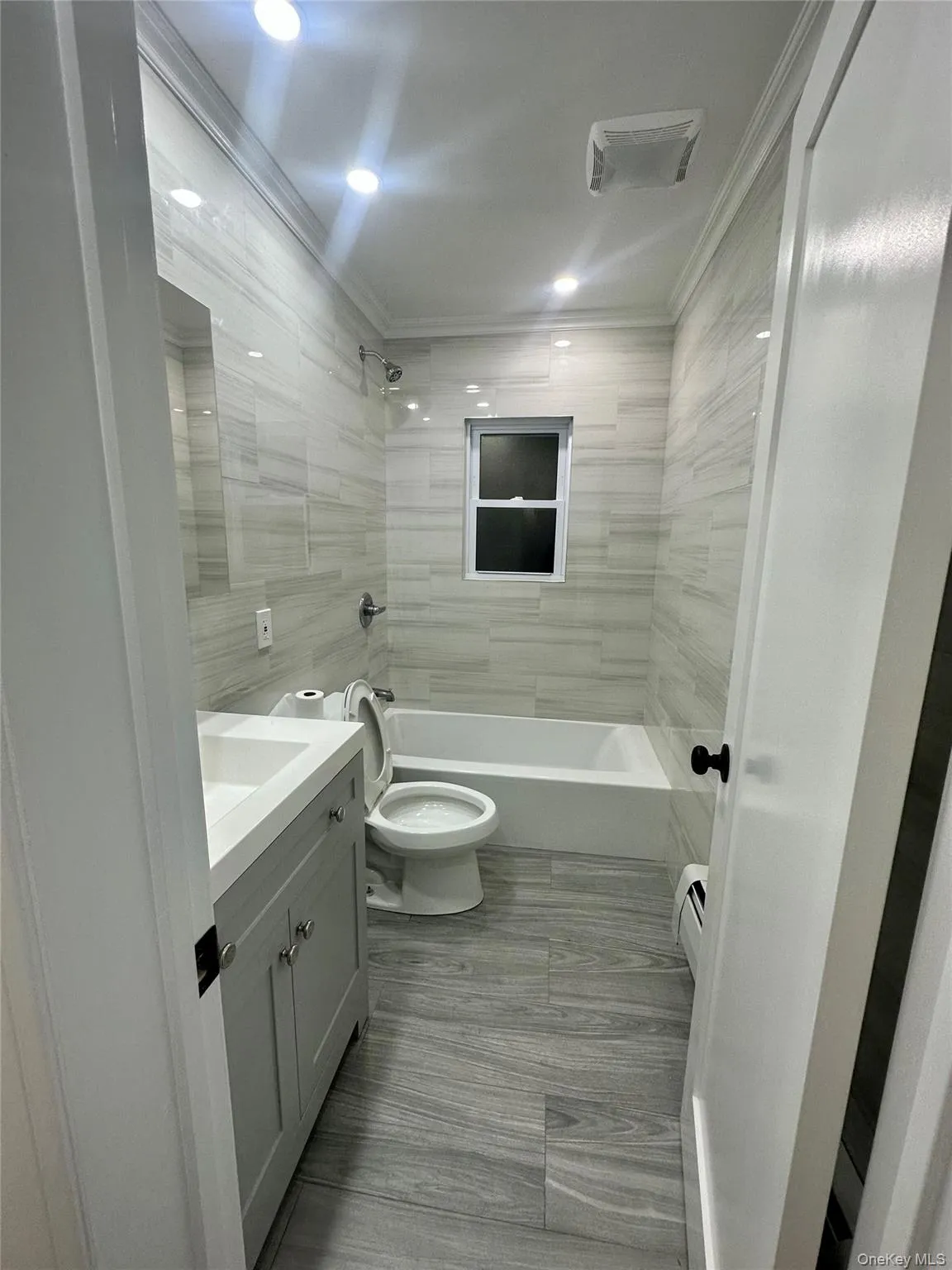 Full bathroom with tile walls, toilet, shower / washtub combination, vanity, and crown molding Full bathroom with tile walls, toilet, shower / washtub combination, vanity, and crown molding