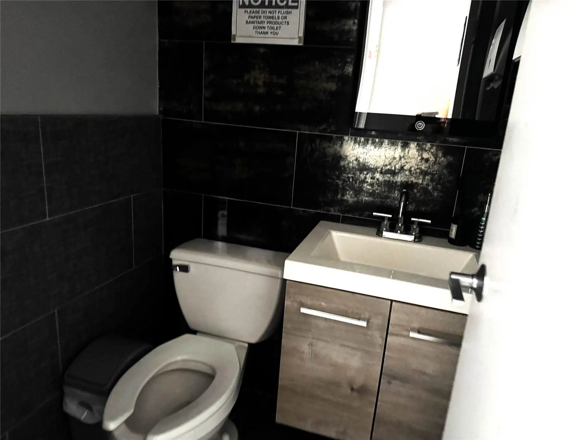 Half bathroom featuring toilet, tile walls, vanity, and decorative backsplash Half bathroom featuring toilet, tile walls, vanity, and decorative backsplash