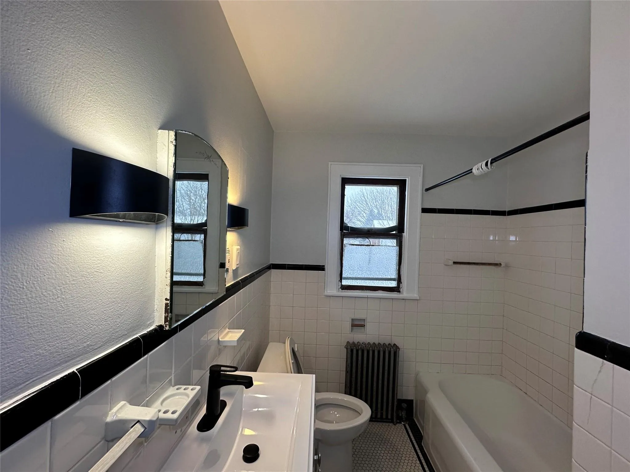 Full bath featuring tile walls, toilet, tile patterned flooring, and radiator Full bath featuring tile walls, toilet, tile patterned flooring, and radiator