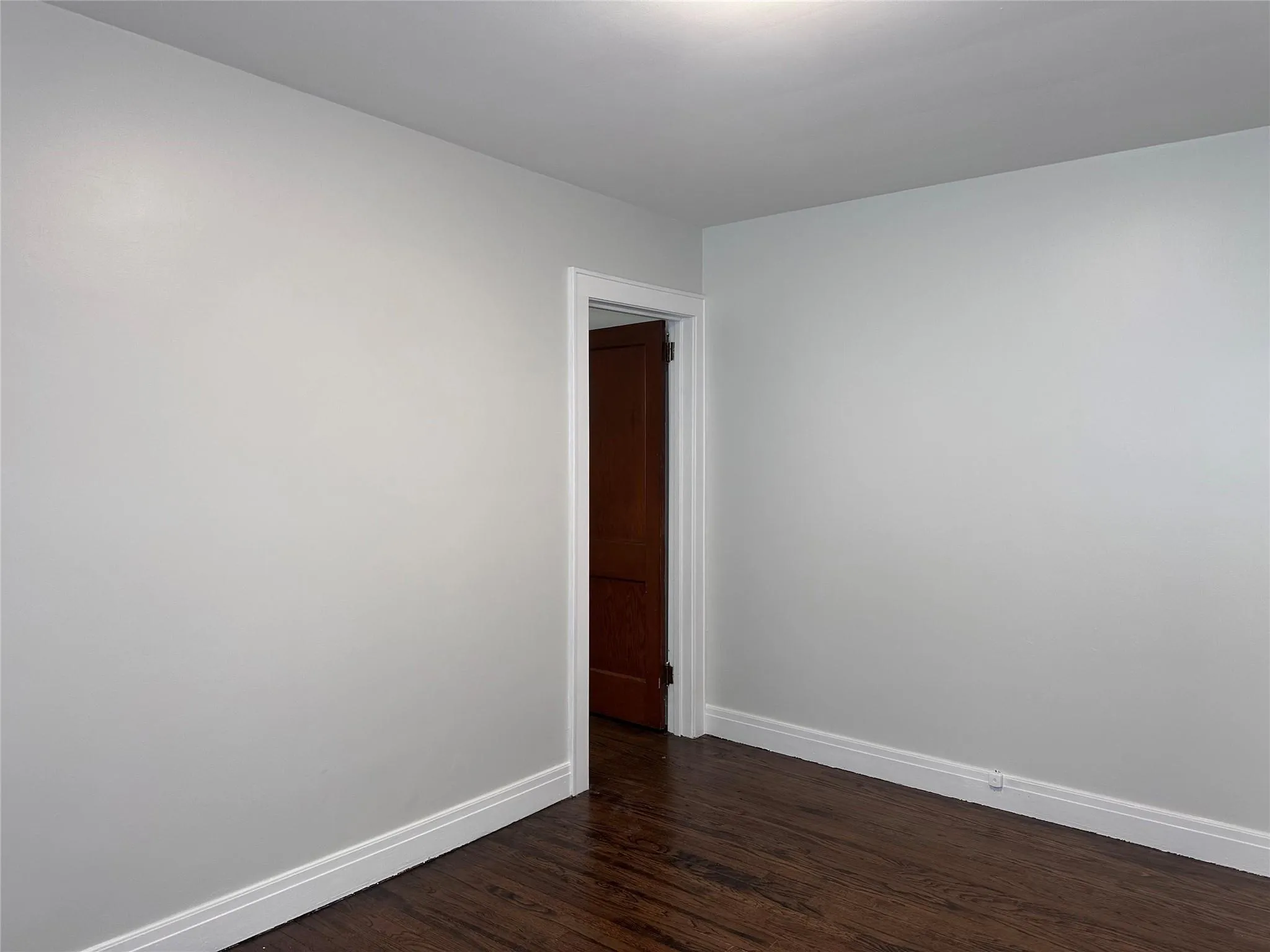 Spare room featuring baseboards and dark wood-style flooring Spare room featuring baseboards and dark wood-style flooring