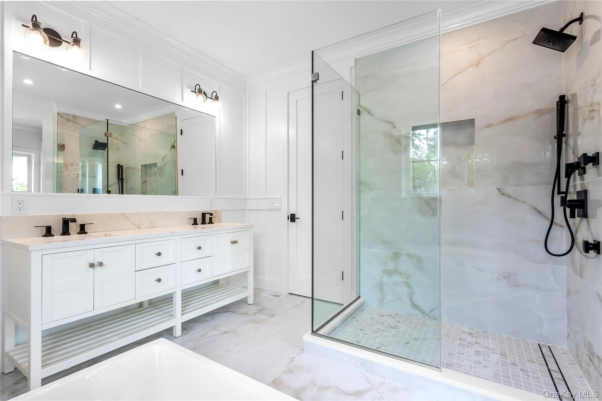 Full bath with a marble finish shower, crown molding, marble finish flooring, double vanity, and plenty of natural light Full bath with a marble finish shower, crown molding, marble finish flooring, double vanity, and plenty of natural light