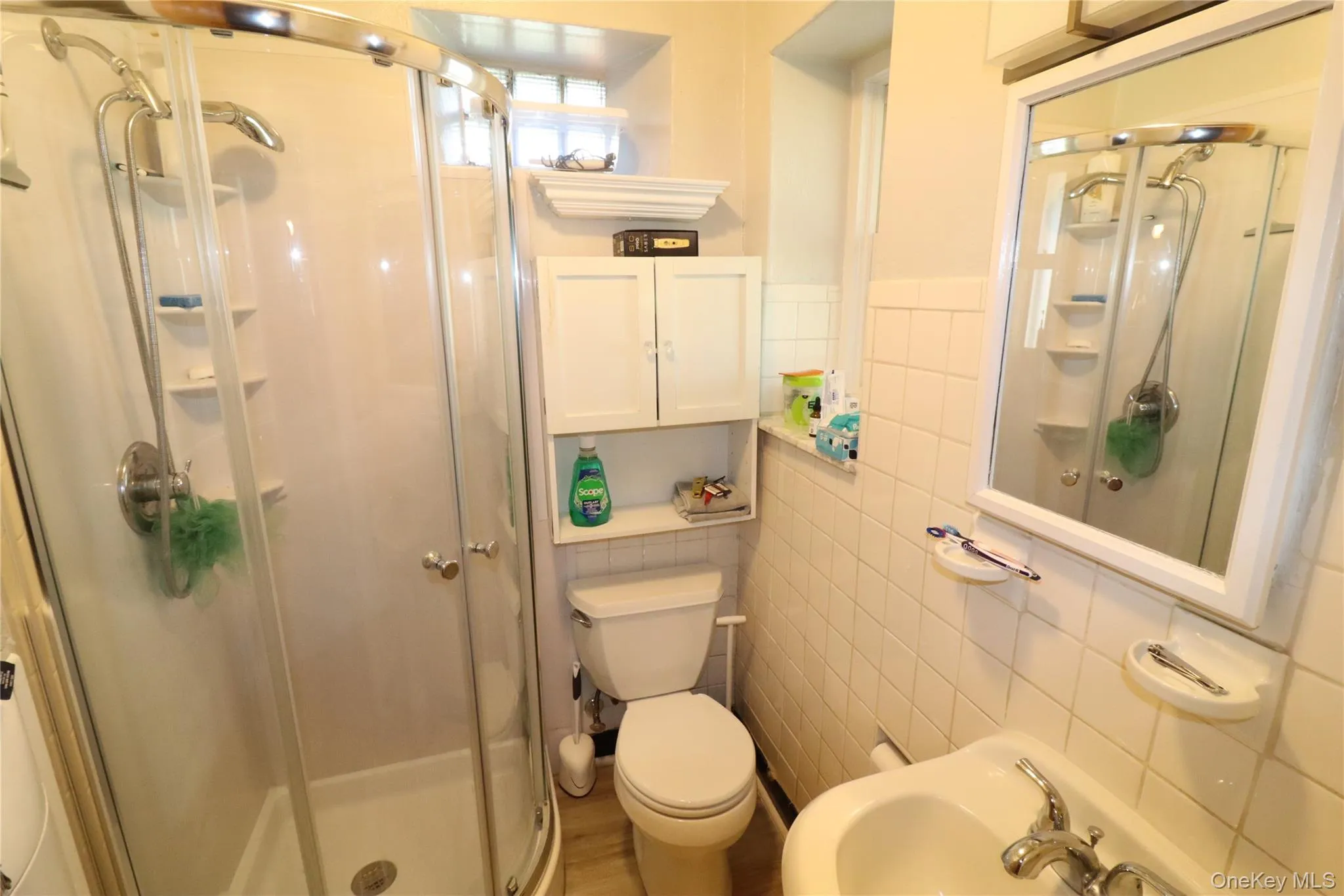 Full bath featuring tile walls, a stall shower, and a sink Full bath featuring tile walls, a stall shower, and a sink