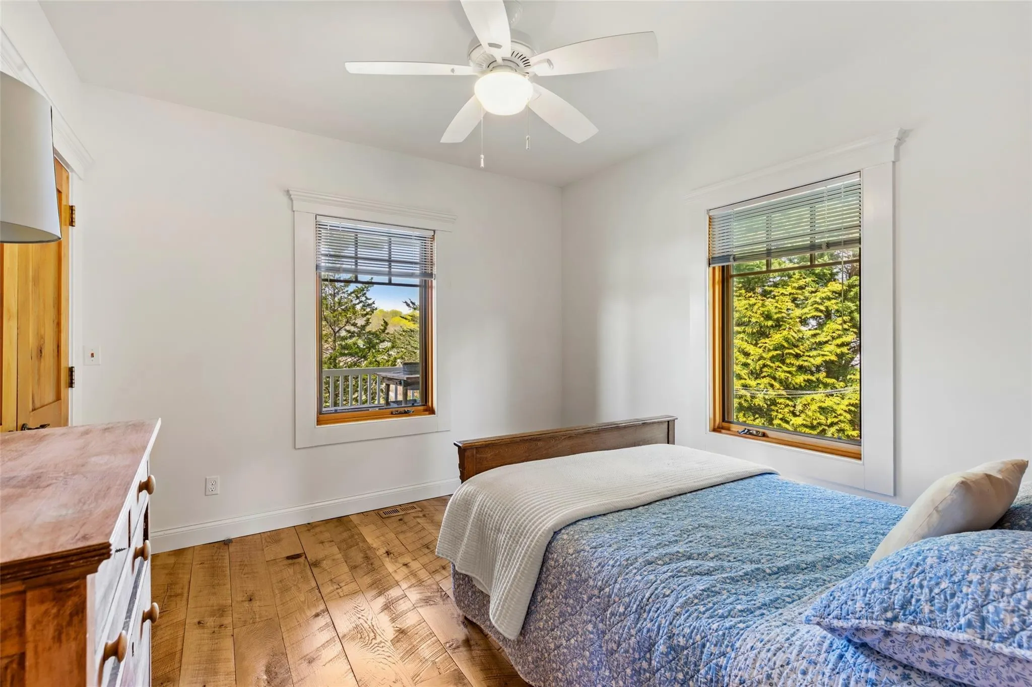 Bedroom featuring baseboards, multiple windows, a ceiling fan, and light wood-style flooring Bedroom featuring baseboards, multiple windows, a ceiling fan, and light wood-style flooring