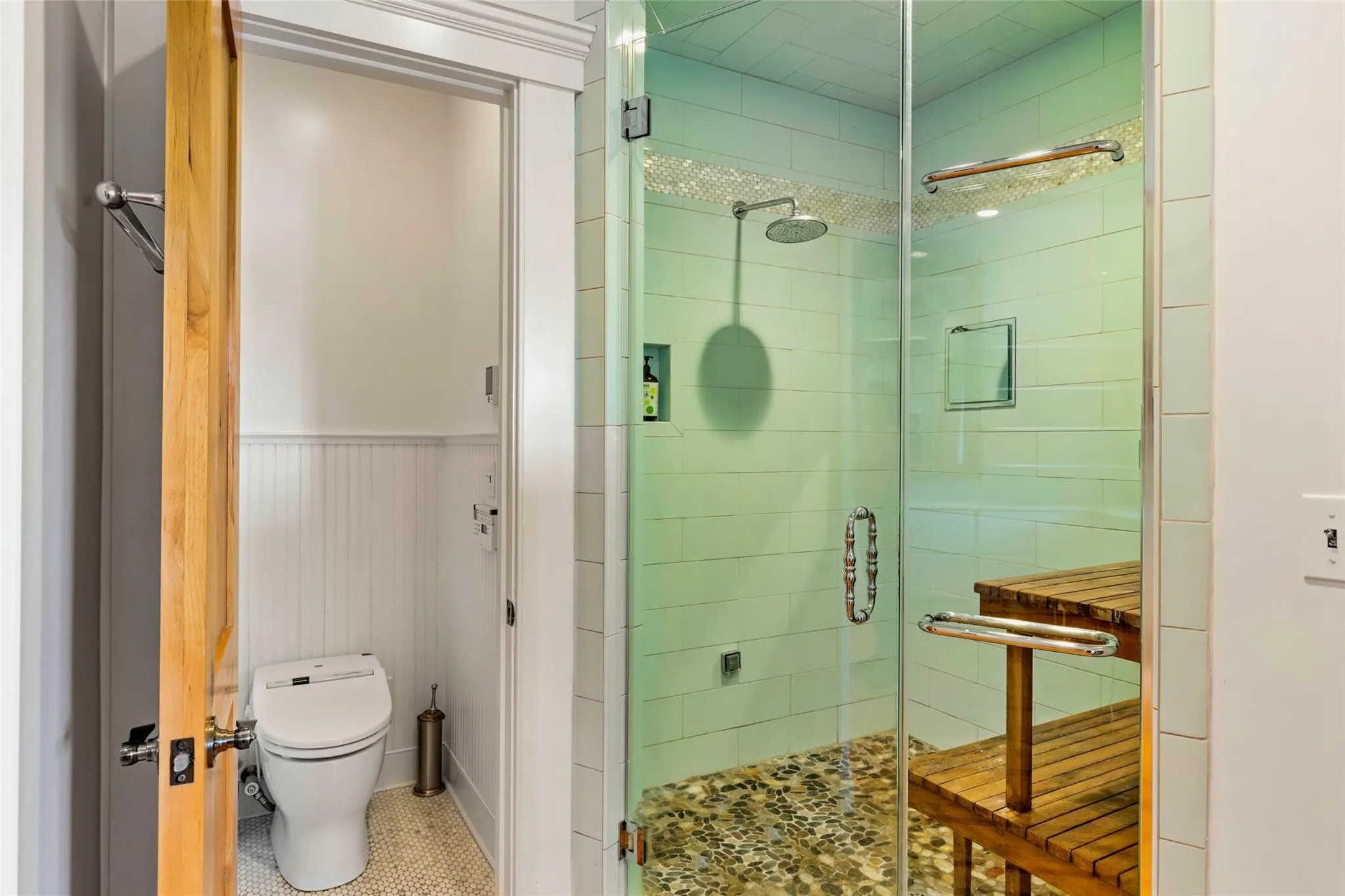Bathroom featuring toilet, a shower stall, tile patterned flooring, and a wainscoted wall Bathroom featuring toilet, a shower stall, tile patterned flooring, and a wainscoted wall