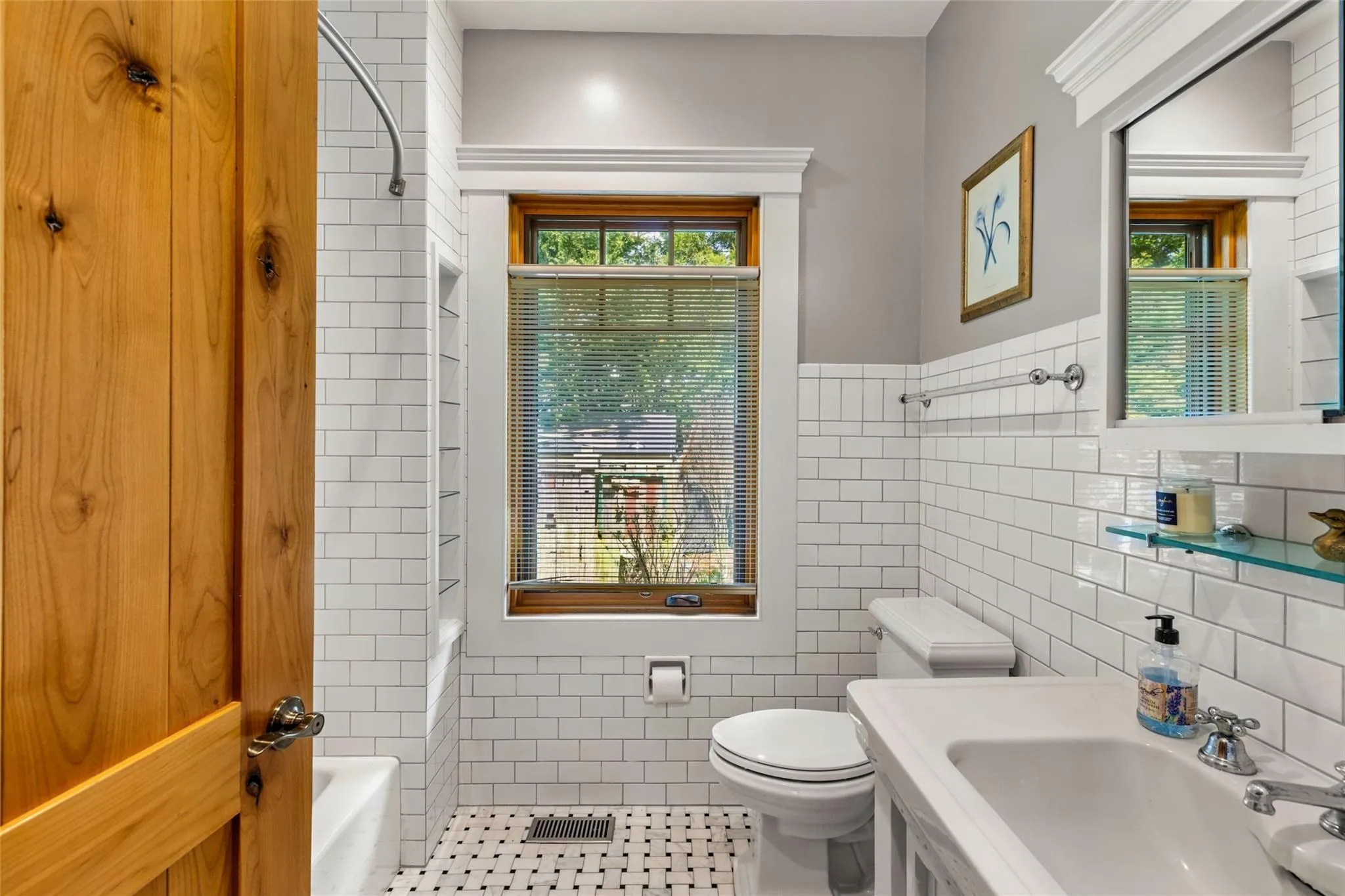 Bathroom featuring tile patterned flooring, toilet, tile walls, a tub to relax in, and a sink Bathroom featuring tile patterned flooring, toilet, tile walls, a tub to relax in, and a sink