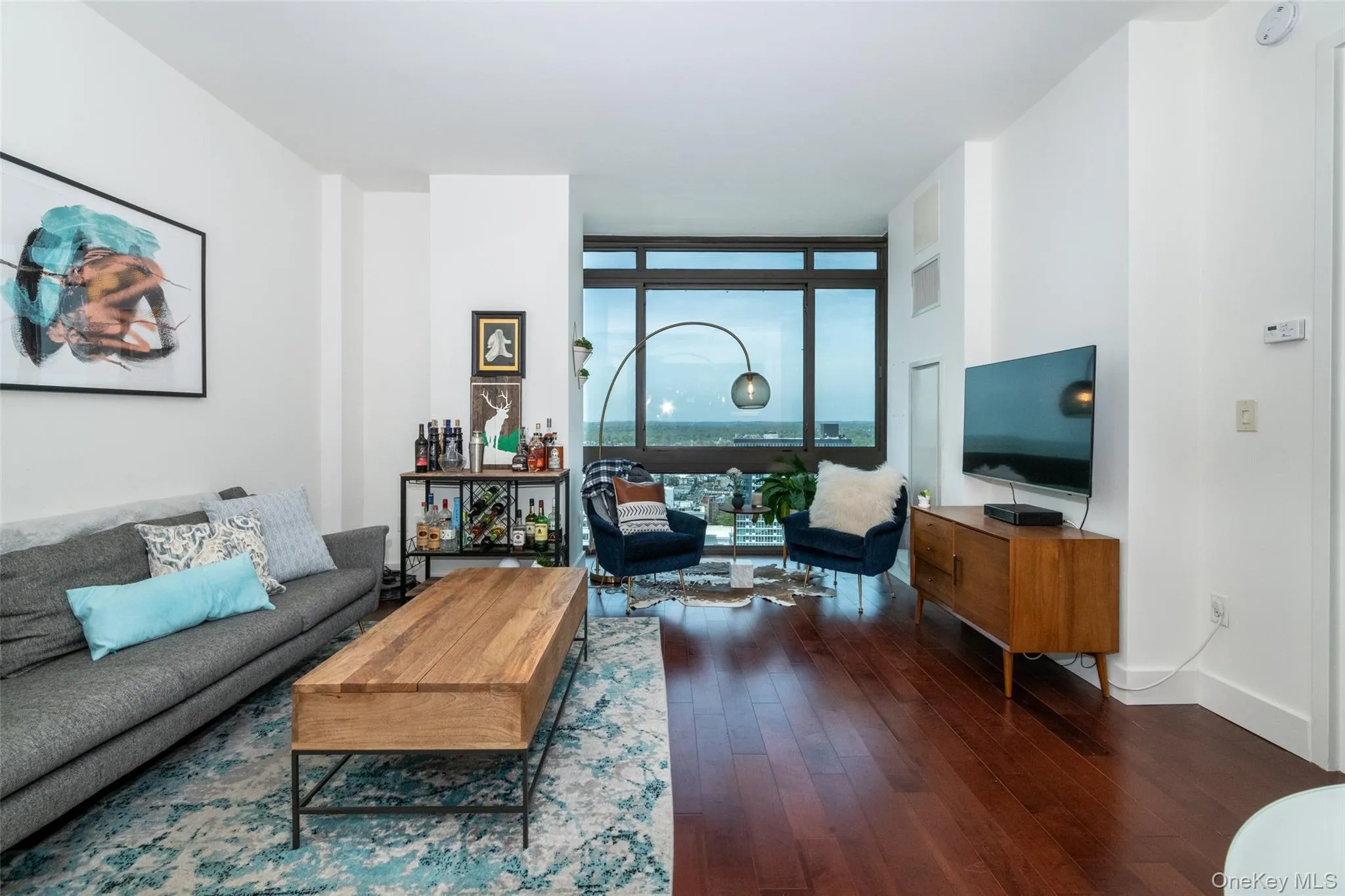 Living room with expansive windows, wood-type flooring, and baseboards Living room with expansive windows, wood-type flooring, and baseboards