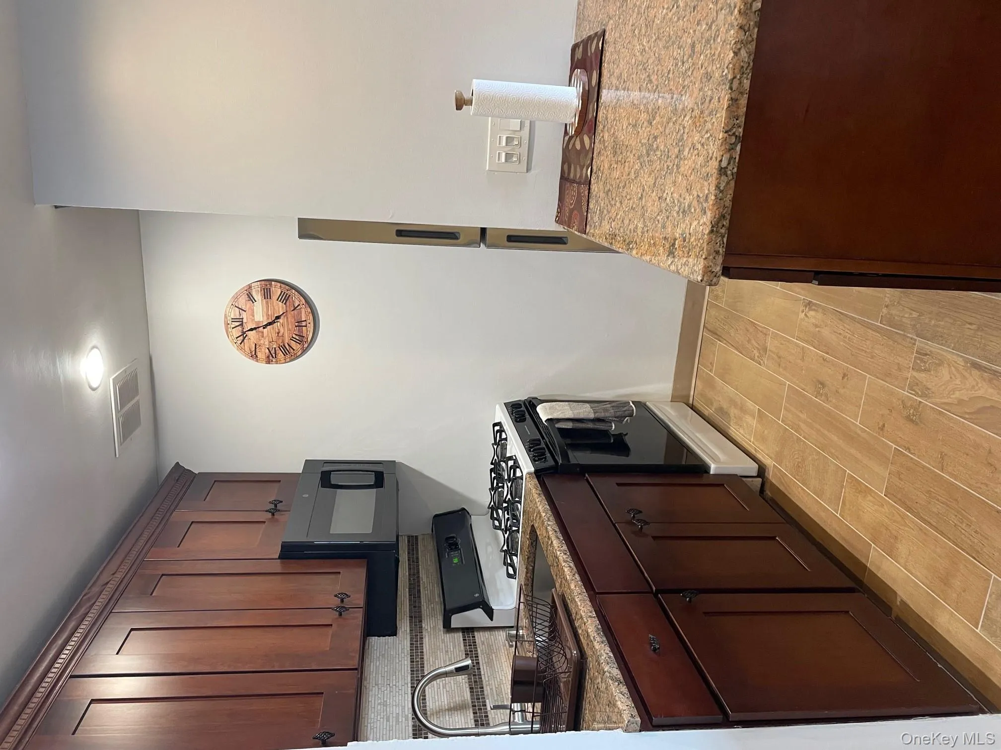 Kitchen featuring visible vents, range, dark brown cabinets, a sink, and light wood-style floors Kitchen featuring visible vents, range, dark brown cabinets, a sink, and light wood-style floors