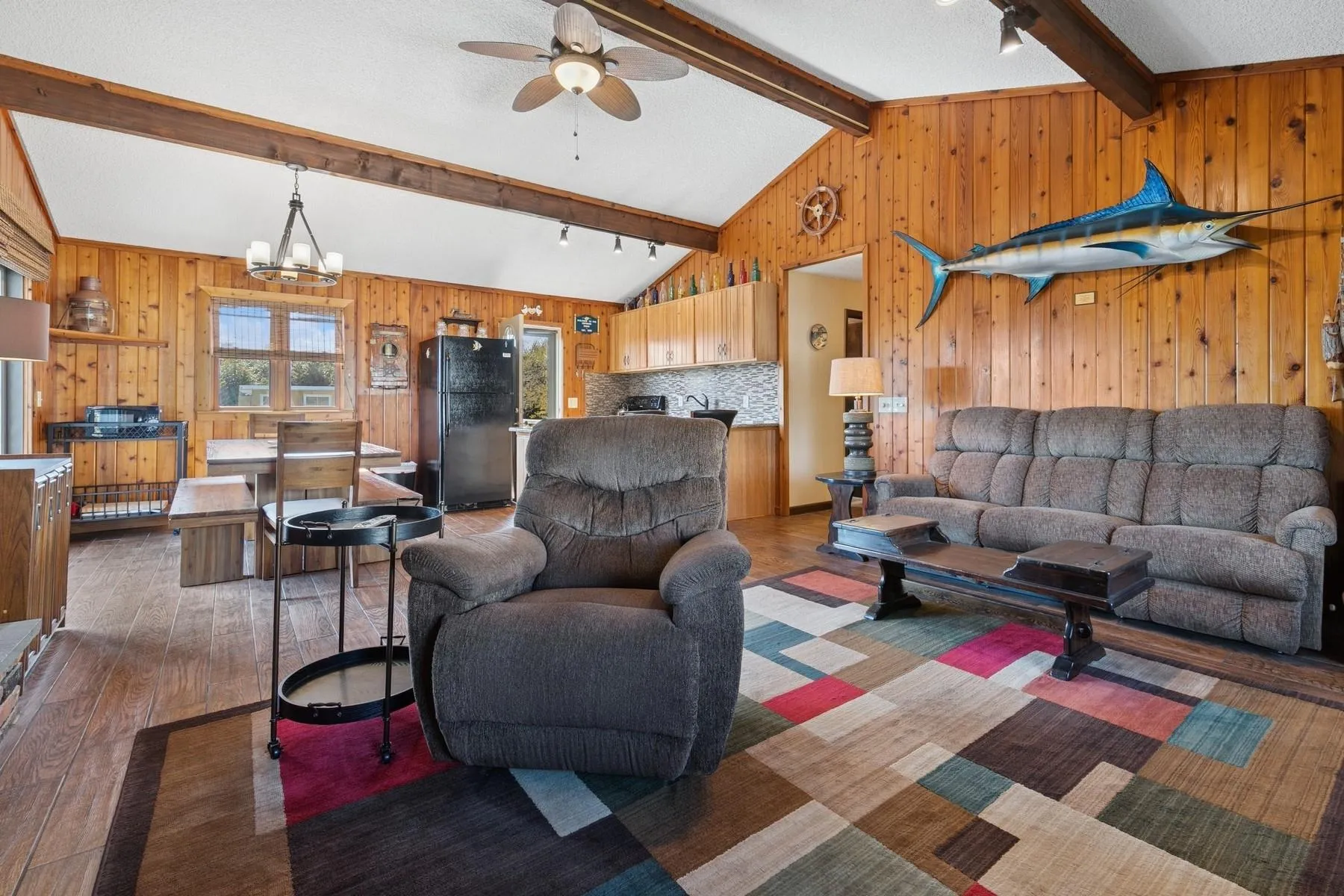Living room with wood walls, lofted ceiling with beams, and hardwood / wood-style flooring Living room with wood walls, lofted ceiling with beams, and hardwood / wood-style flooring