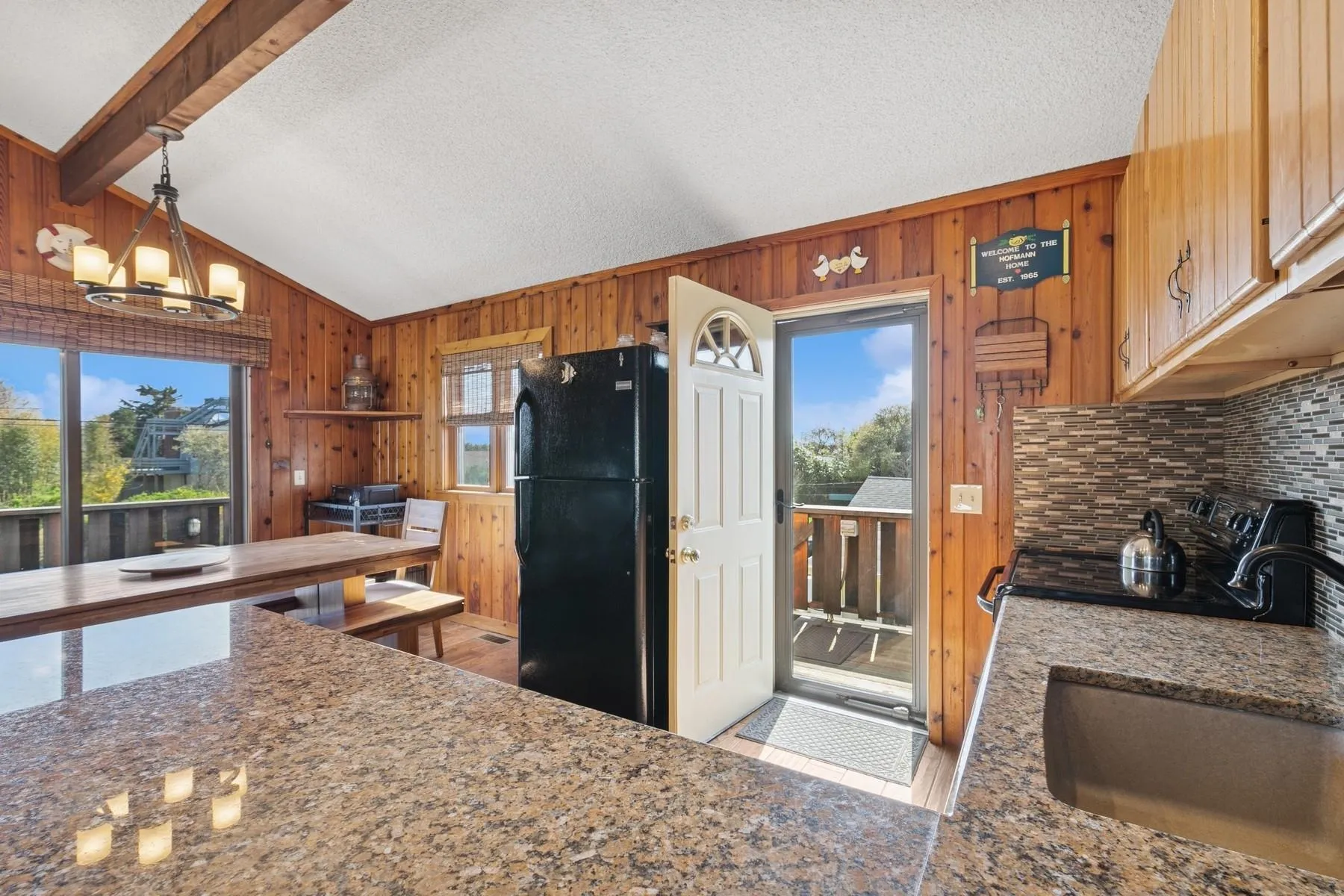 Kitchen featuring freestanding refrigerator, wooden walls, a sink, and vaulted ceiling with beams Kitchen featuring freestanding refrigerator, wooden walls, a sink, and vaulted ceiling with beams