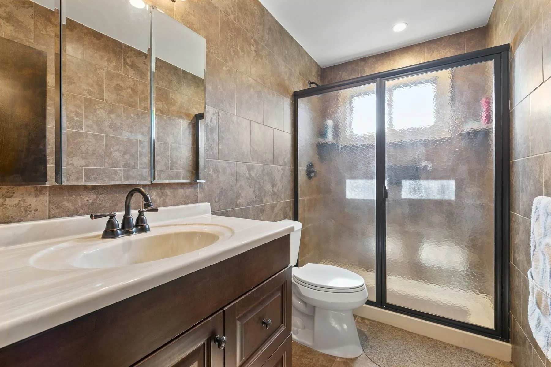 Full bath with vanity, tile walls, a stall shower, and toilet Full bath with vanity, tile walls, a stall shower, and toilet