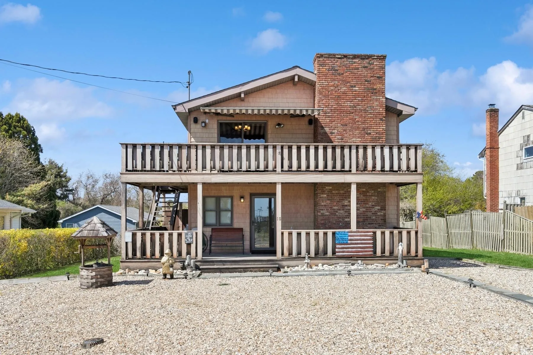 View of front of property featuring fence, a porch, stairway, a chimney, and a balcony View of front of property featuring fence, a porch, stairway, a chimney, and a balcony