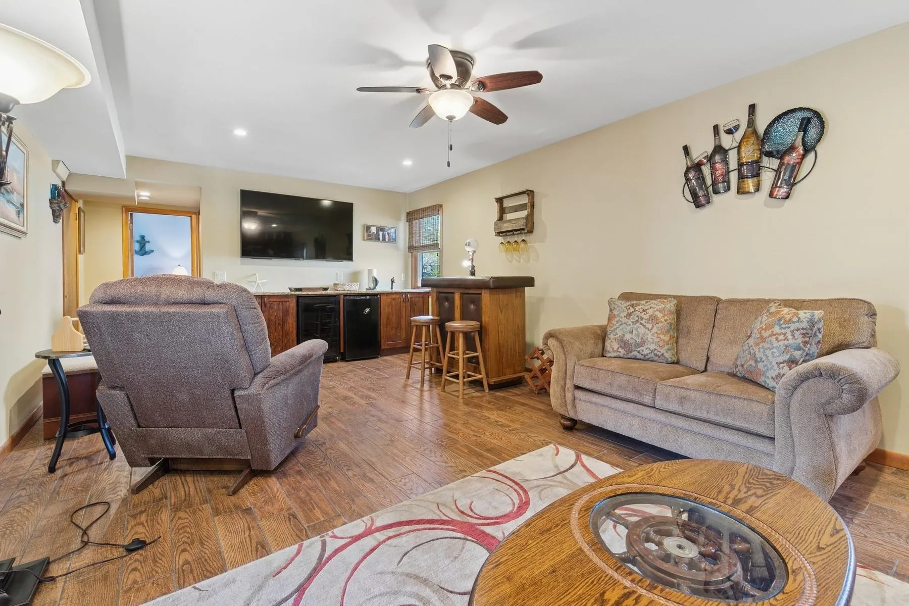 Living room with indoor wet bar, recessed lighting, ceiling fan, and wood finished floors Living room with indoor wet bar, recessed lighting, ceiling fan, and wood finished floors