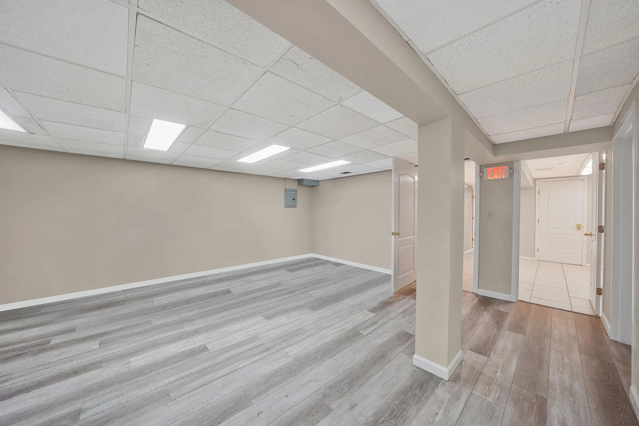Finished below grade area with baseboards, light wood-style flooring, and a paneled ceiling Finished below grade area with baseboards, light wood-style flooring, and a paneled ceiling