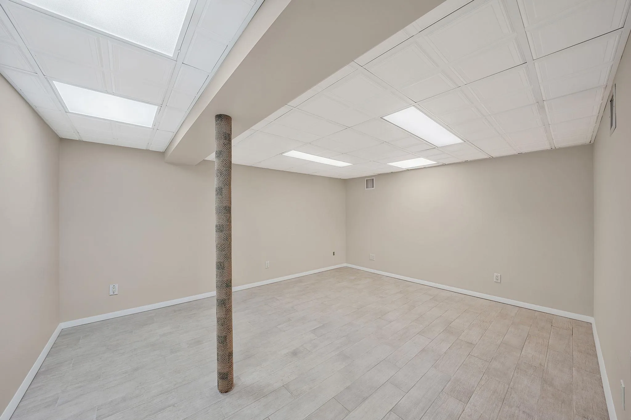 Finished basement with baseboards, wood finished floors, and visible vents Finished basement with baseboards, wood finished floors, and visible vents