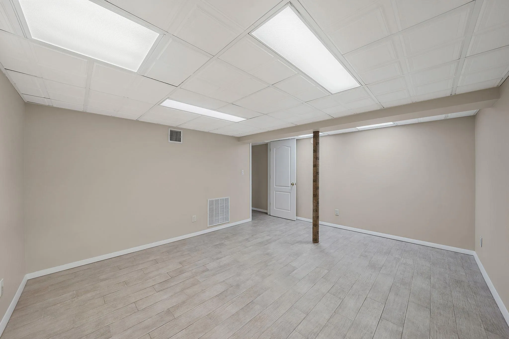 Finished below grade area featuring visible vents, baseboards, and wood finished floors Finished below grade area featuring visible vents, baseboards, and wood finished floors