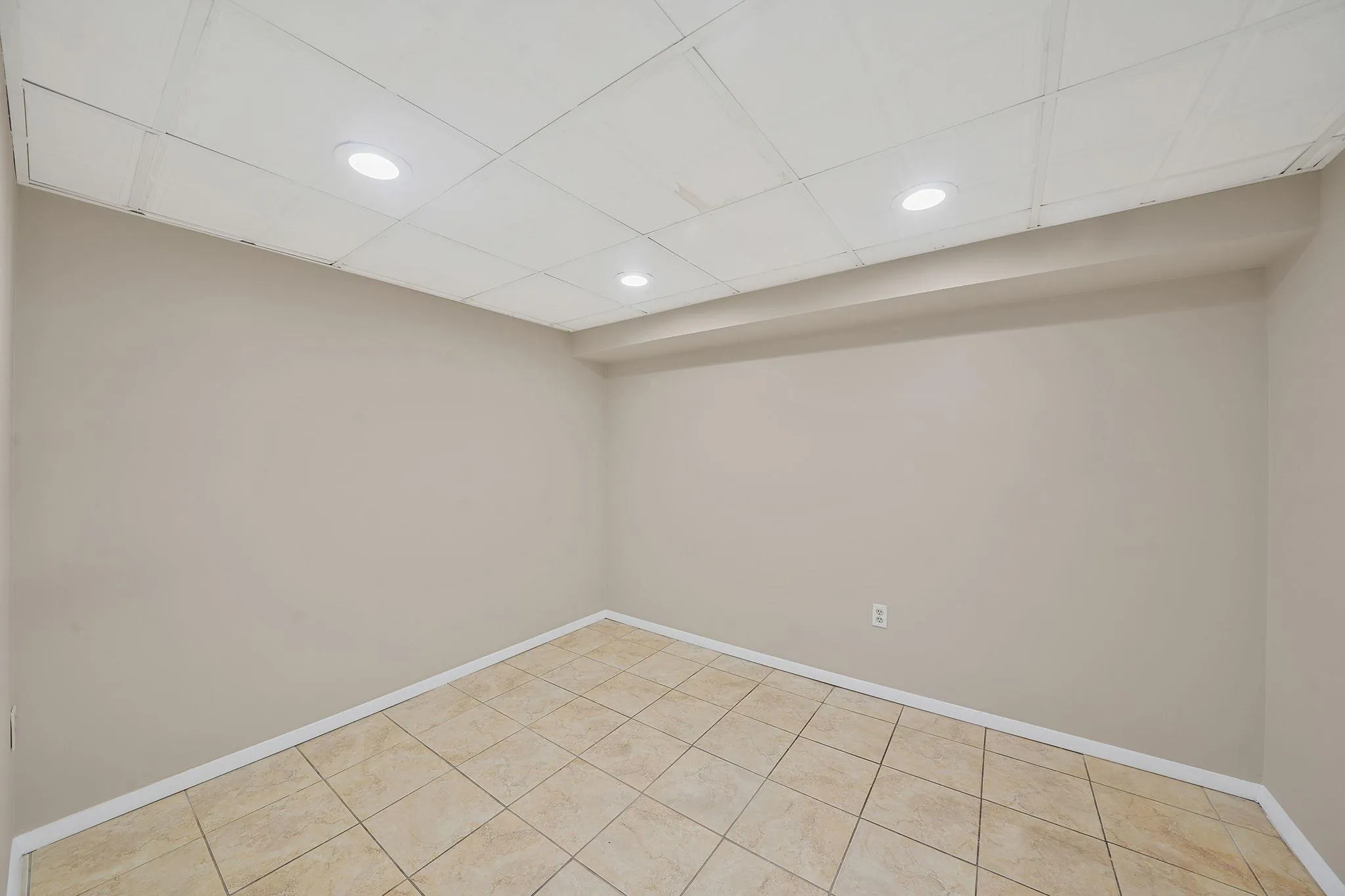 Finished basement featuring recessed lighting, baseboards, a drop ceiling, and light tile patterned floors Finished basement featuring recessed lighting, baseboards, a drop ceiling, and light tile patterned floors