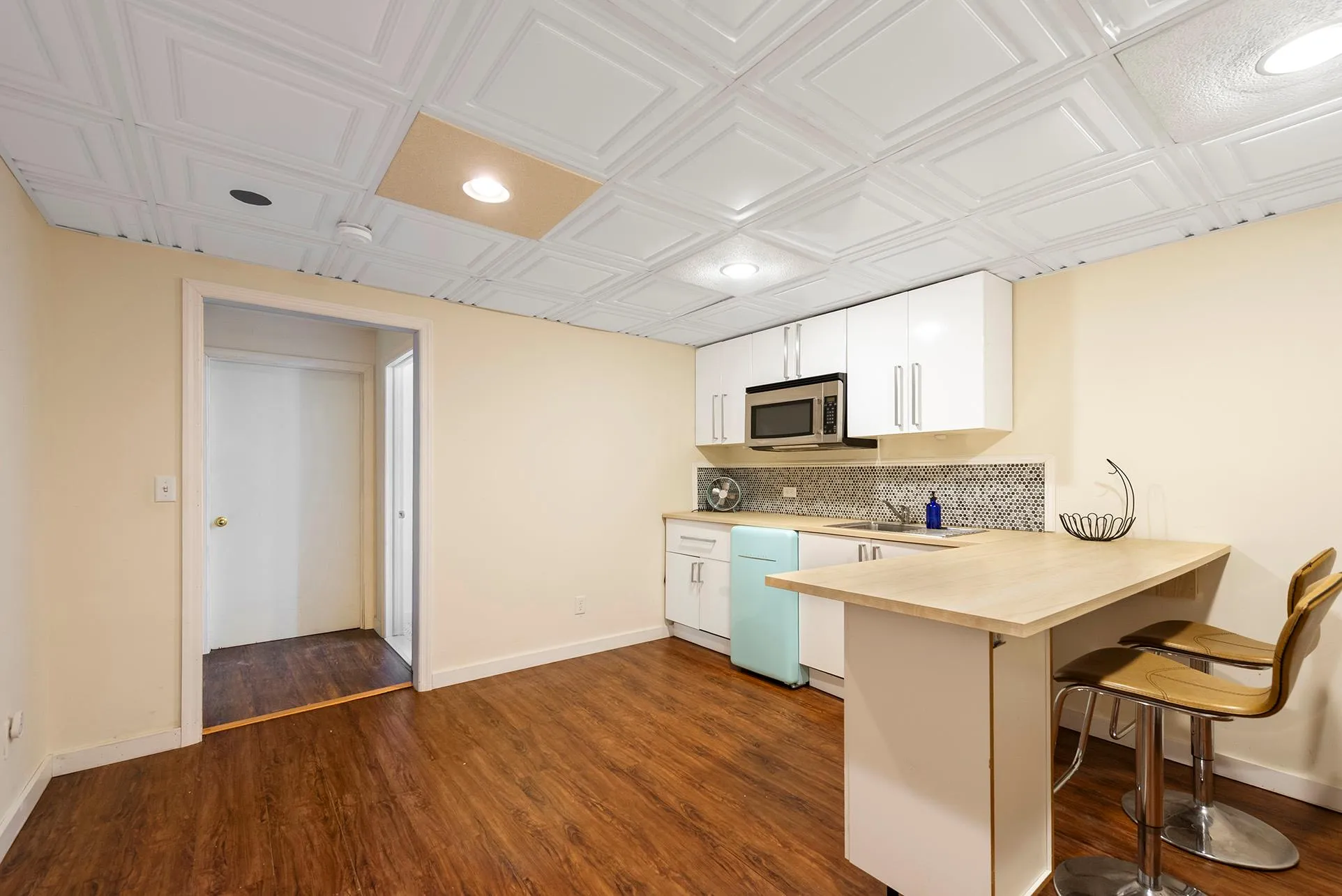 Kitchen featuring stainless steel microwave, light countertops, baseboards, a kitchen bar, and an ornate ceiling Kitchen featuring stainless steel microwave, light countertops, baseboards, a kitchen bar, and an ornate ceiling