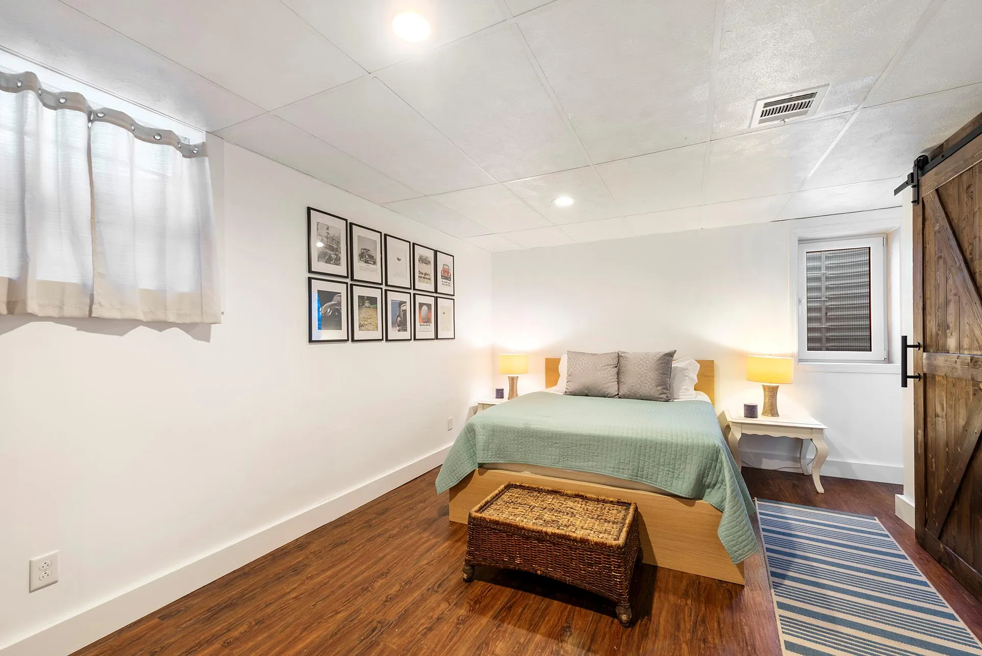 Bedroom with a barn door, baseboards, wood finished floors, recessed lighting, and a paneled ceiling Bedroom with a barn door, baseboards, wood finished floors, recessed lighting, and a paneled ceiling