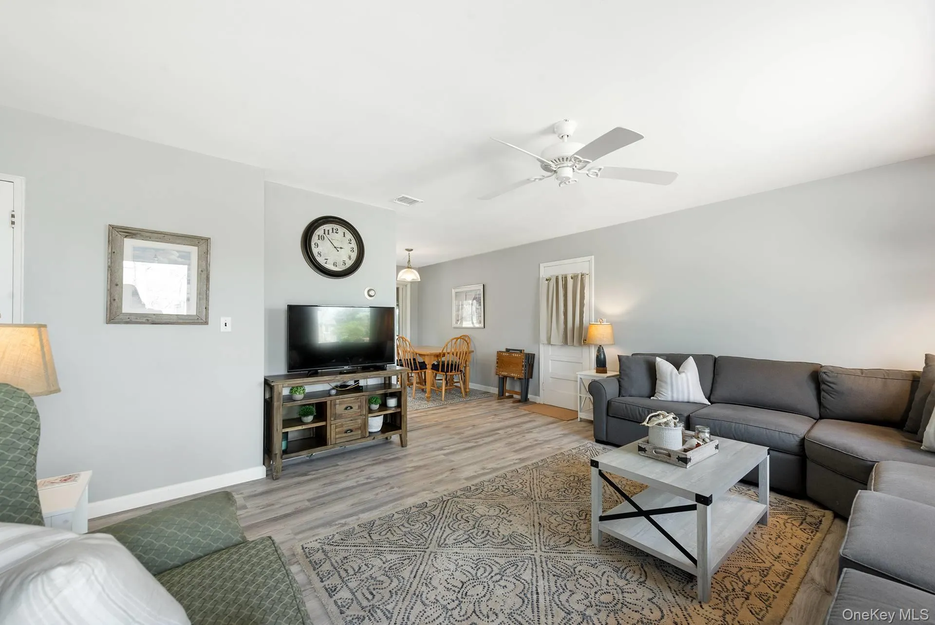 Living area featuring light wood-style floors, baseboards, a ceiling fan, and visible vents Living area featuring light wood-style floors, baseboards, a ceiling fan, and visible vents