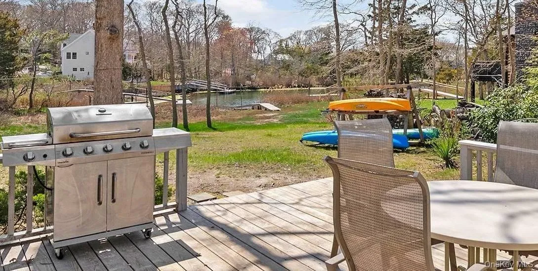 Wooden deck featuring outdoor dining area, a water view, and a yard Wooden deck featuring outdoor dining area, a water view, and a yard