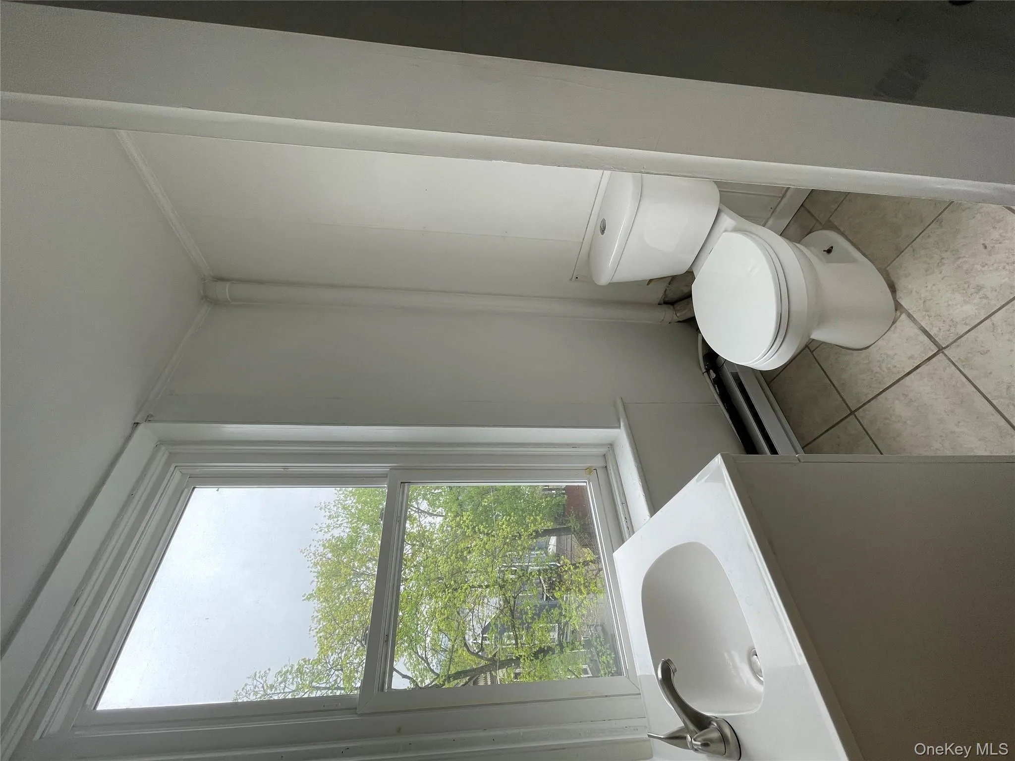 Bathroom featuring a sink, tile patterned floors, a baseboard heating unit, and toilet Bathroom featuring a sink, tile patterned floors, a baseboard heating unit, and toilet