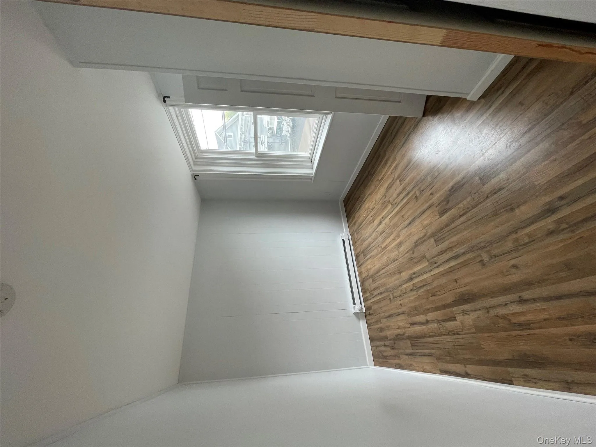 Spare room with baseboards, a baseboard radiator, and dark wood-style flooring Spare room with baseboards, a baseboard radiator, and dark wood-style flooring