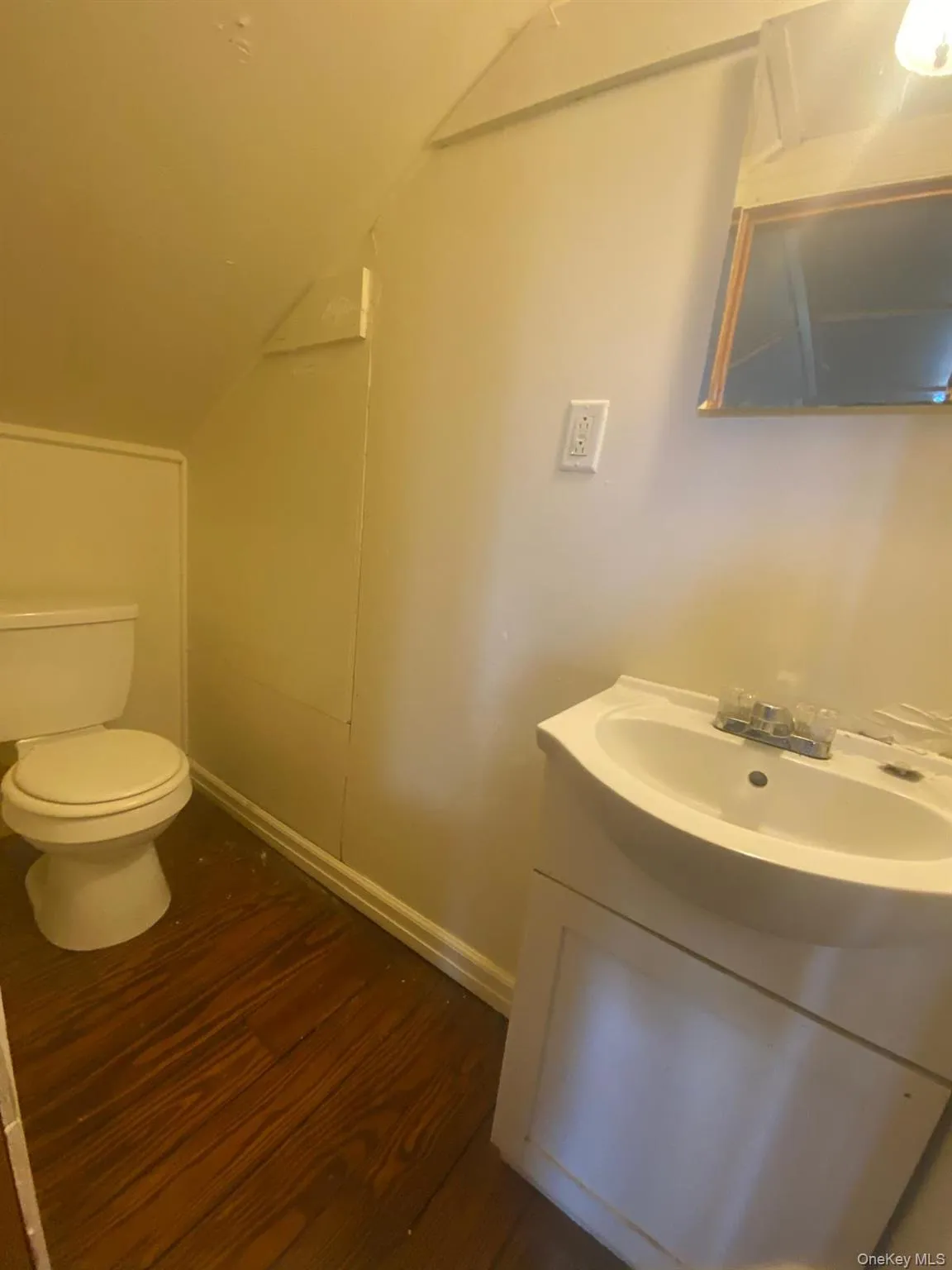 Bathroom featuring vanity, toilet, baseboards, wood finished floors, and vaulted ceiling Bathroom featuring vanity, toilet, baseboards, wood finished floors, and vaulted ceiling