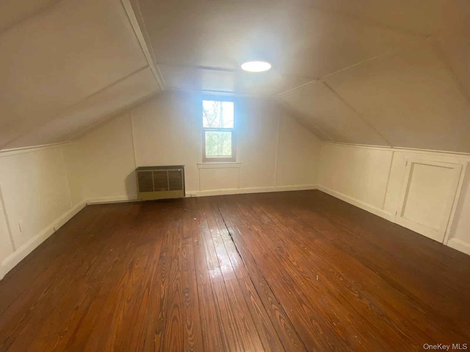 Additional living space featuring baseboards, vaulted ceiling, dark wood-style floors, and heating unit Additional living space featuring baseboards, vaulted ceiling, dark wood-style floors, and heating unit