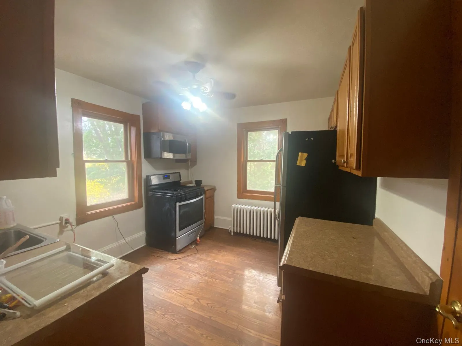 Kitchen with brown cabinets, a sink, radiator, stainless steel appliances, and light wood-style flooring Kitchen with brown cabinets, a sink, radiator, stainless steel appliances, and light wood-style flooring