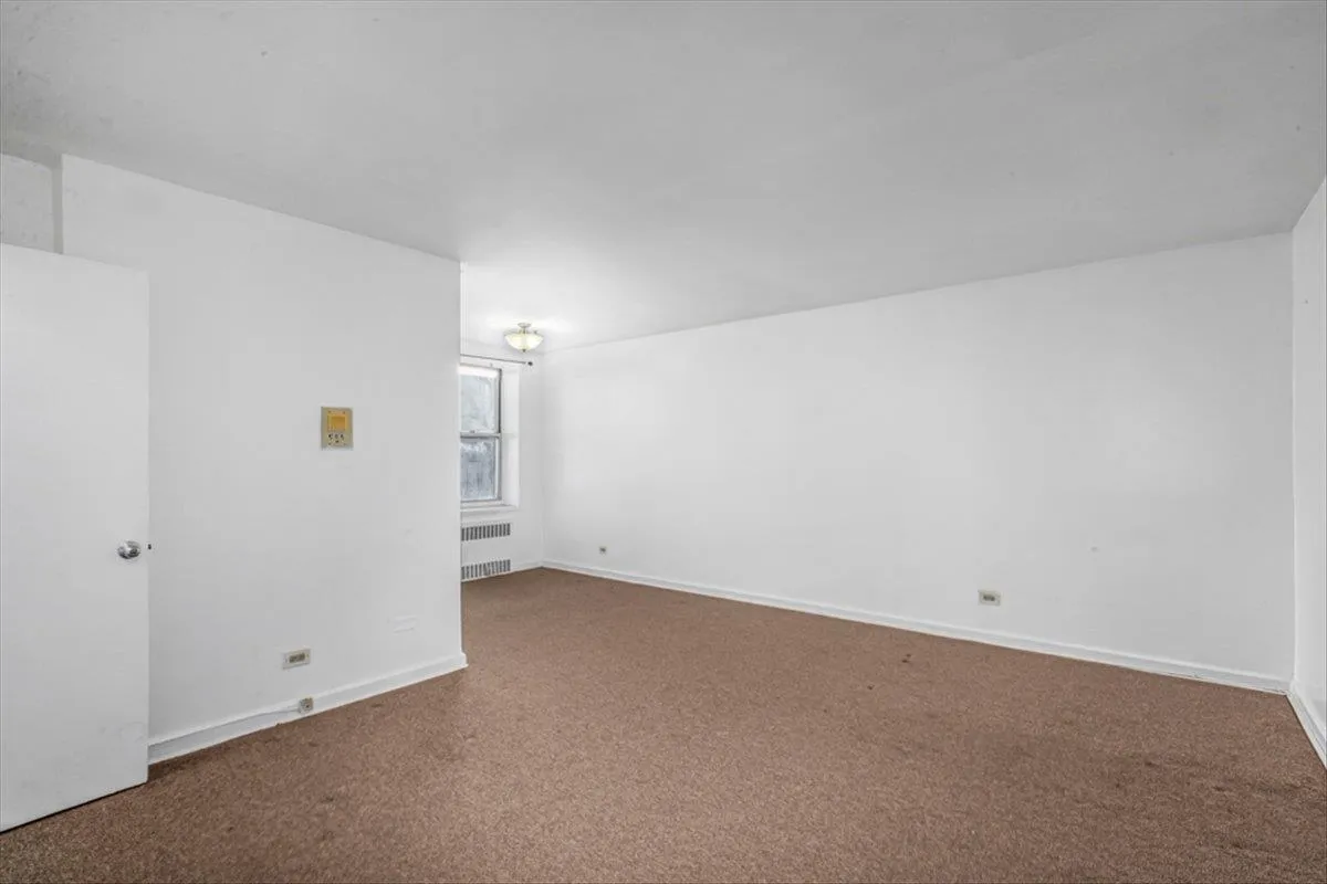 Unfurnished room with carpet floors and radiator Unfurnished room with carpet floors and radiator