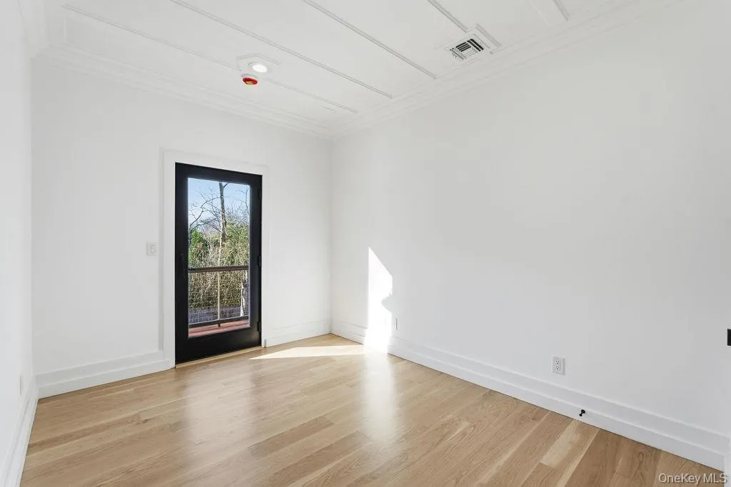 Spare room with light wood-type flooring and crown molding Spare room with light wood-type flooring and crown molding