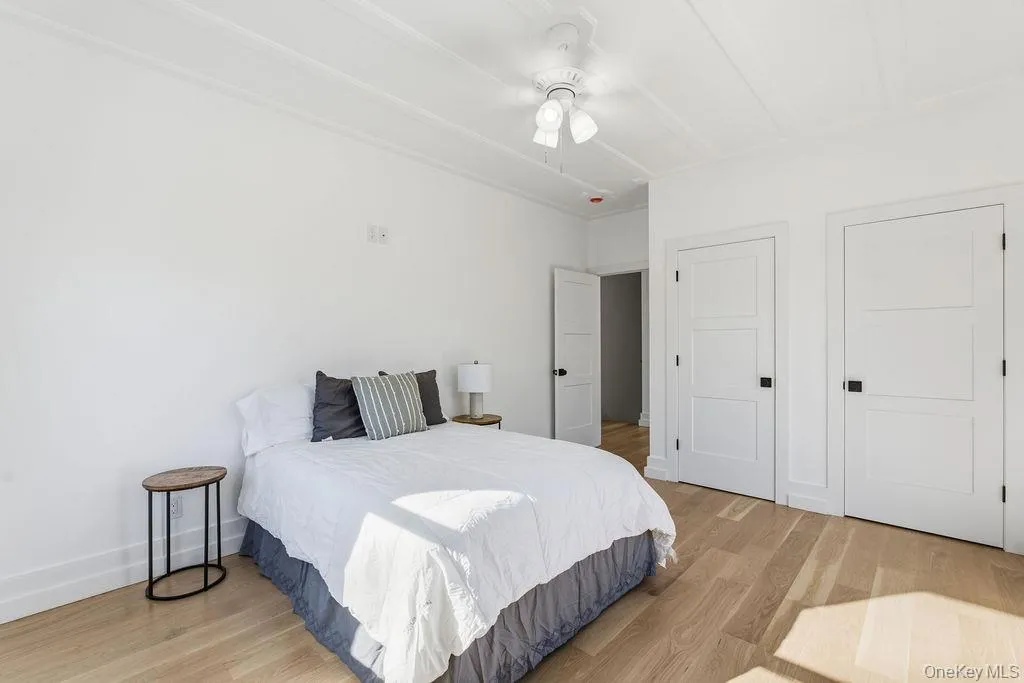 Bedroom with light wood finished floors, two closets, and ceiling fan Bedroom with light wood finished floors, two closets, and ceiling fan