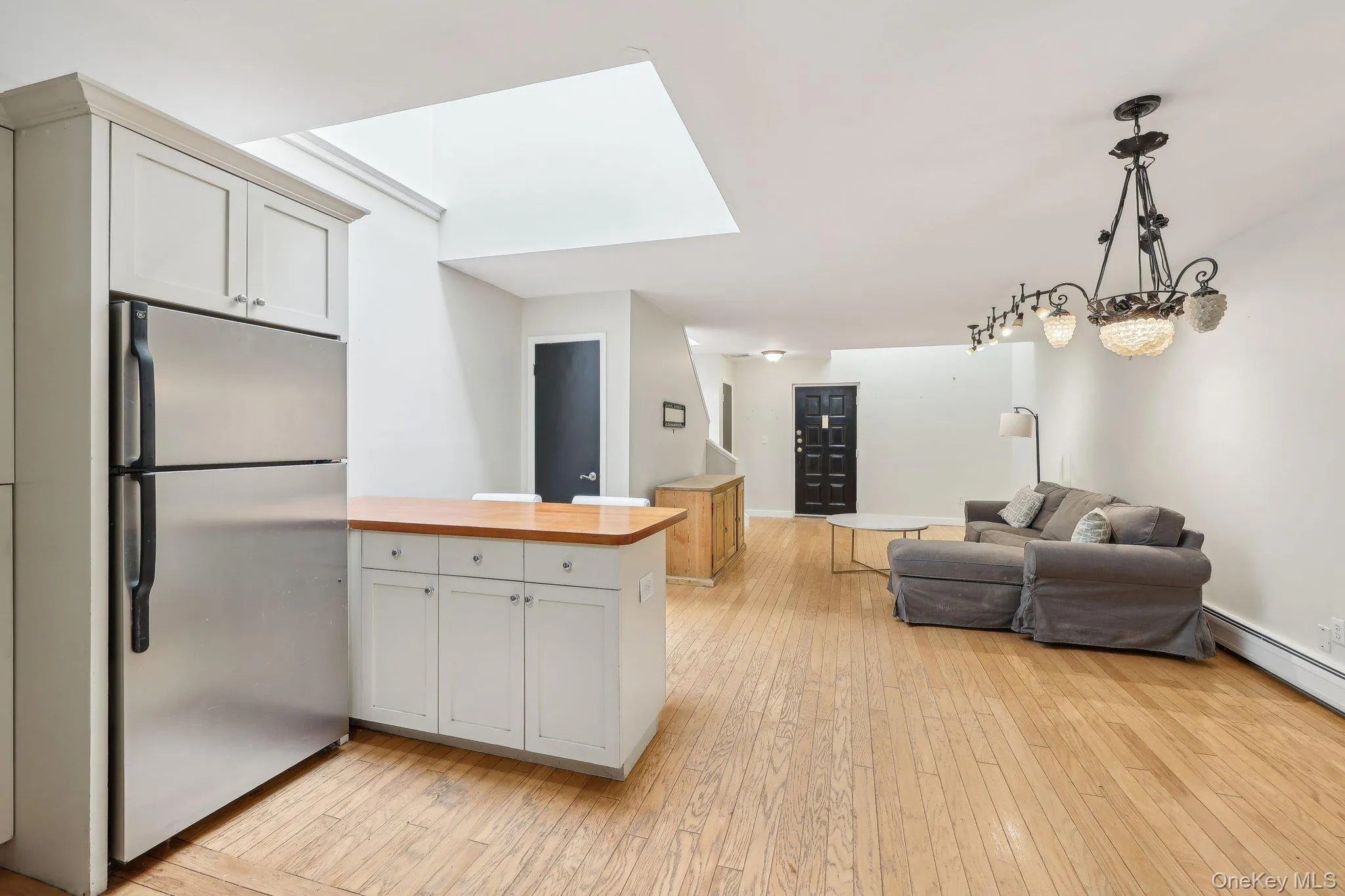 Kitchen featuring wooden counters, open floor plan, stainless steel fridge, light wood finished floors, and a skylight Kitchen featuring wooden counters, open floor plan, stainless steel fridge, light wood finished floors, and a skylight