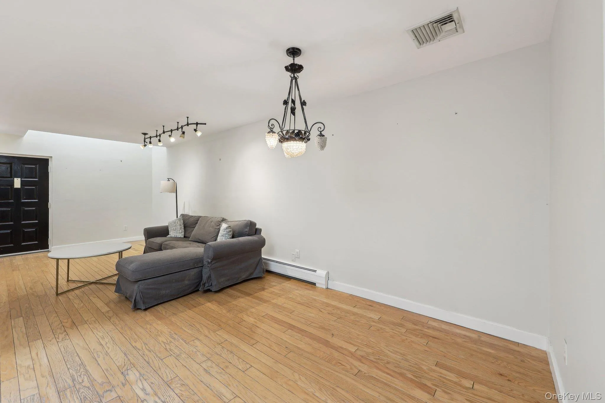 Sitting room featuring visible vents, baseboards, a baseboard heating unit, light wood finished floors, and a notable chandelier Sitting room featuring visible vents, baseboards, a baseboard heating unit, light wood finished floors, and a notable chandelier