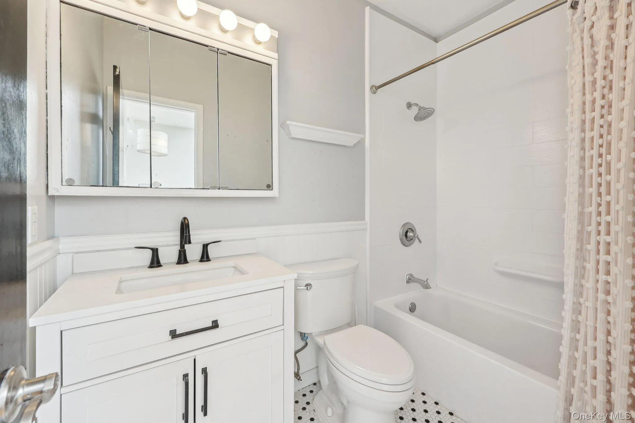 Full bathroom with a wainscoted wall, vanity, toilet, and shower / bath combination with curtain Full bathroom with a wainscoted wall, vanity, toilet, and shower / bath combination with curtain