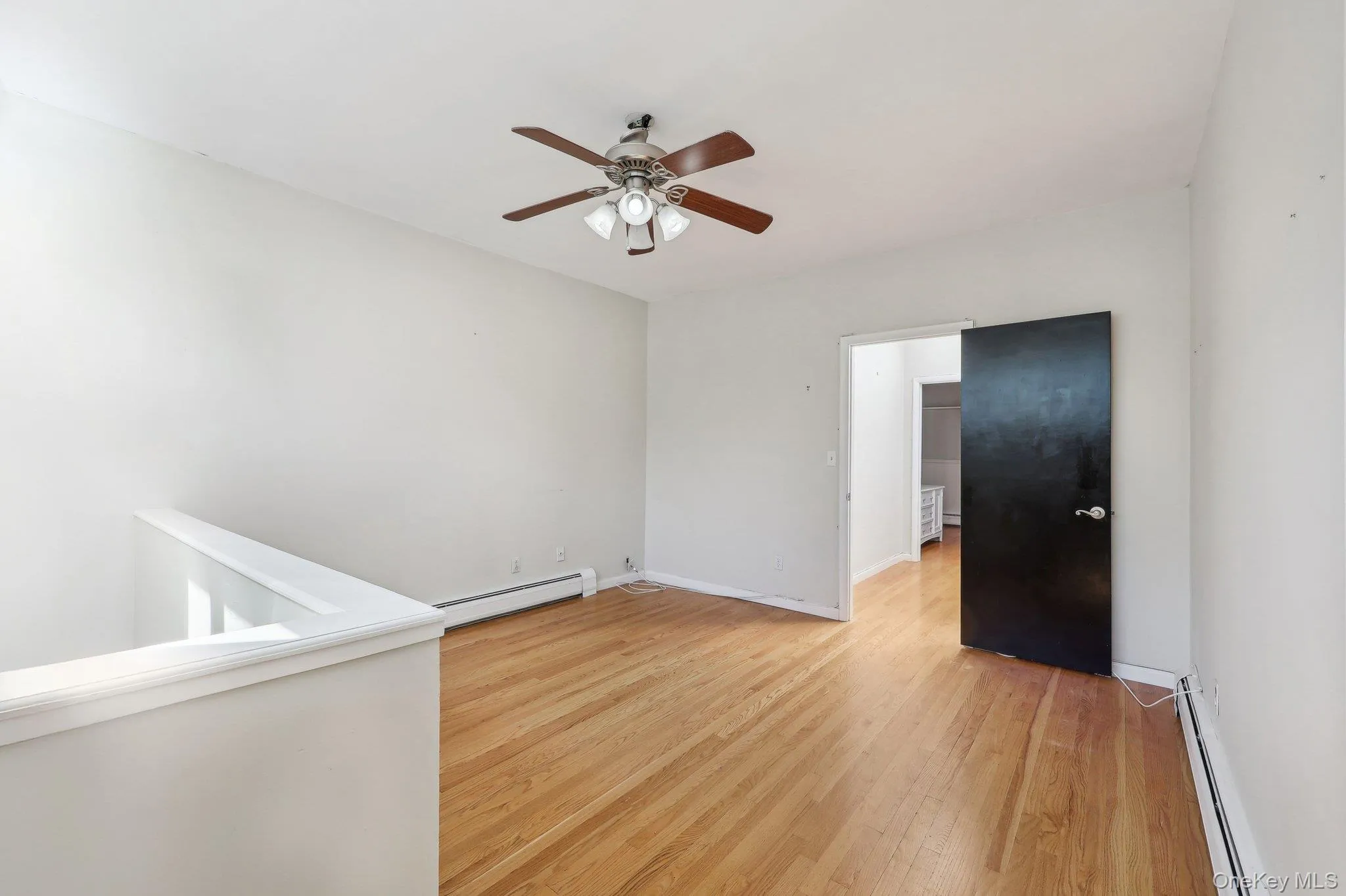 Spare room featuring baseboards, baseboard heating, a baseboard heating unit, a ceiling fan, and light wood finished floors Spare room featuring baseboards, baseboard heating, a baseboard heating unit, a ceiling fan, and light wood finished floors