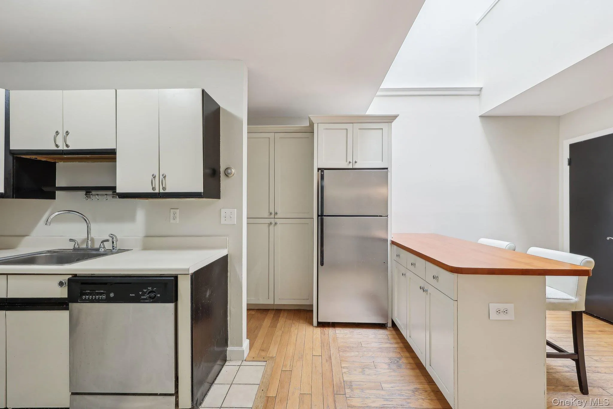 Kitchen with light wood-style floors, a kitchen bar, light countertops, a sink, and appliances with stainless steel finishes Kitchen with light wood-style floors, a kitchen bar, light countertops, a sink, and appliances with stainless steel finishes