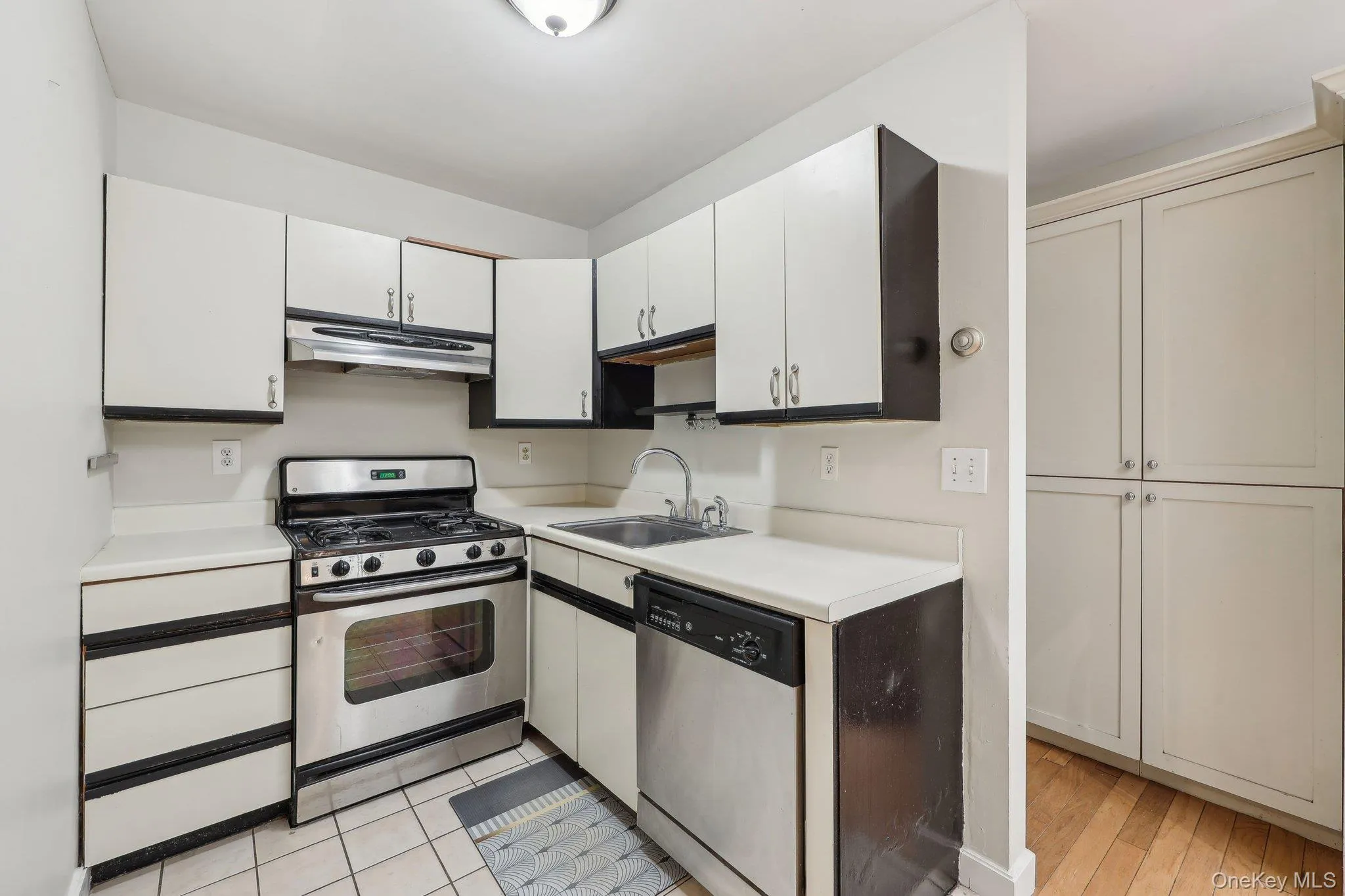 Kitchen featuring under cabinet range hood, appliances with stainless steel finishes, a sink, and light countertops Kitchen featuring under cabinet range hood, appliances with stainless steel finishes, a sink, and light countertops