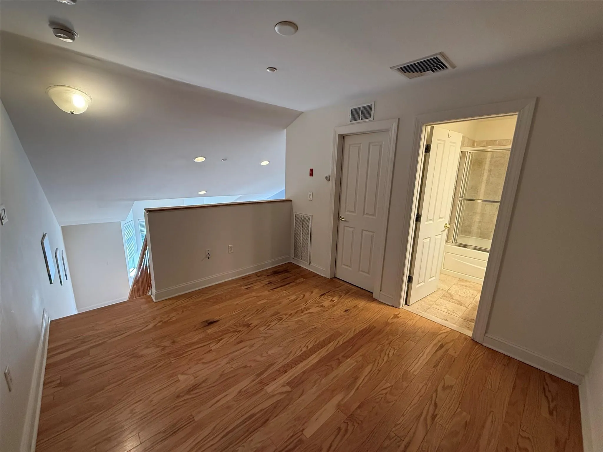 Loft bedroom featuring baseboards, light wood finished floors, and visible vents Loft bedroom featuring baseboards, light wood finished floors, and visible vents
