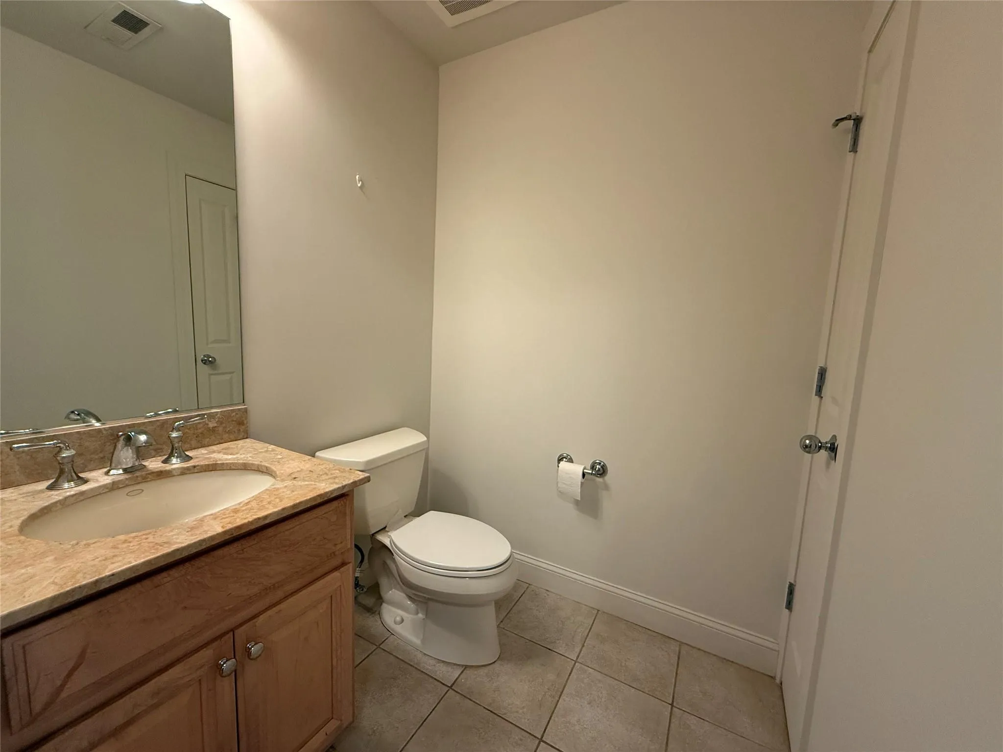 Half bathroom featuring visible vents, tile patterned floors, baseboards, vanity, and toilet Half bathroom featuring visible vents, tile patterned floors, baseboards, vanity, and toilet