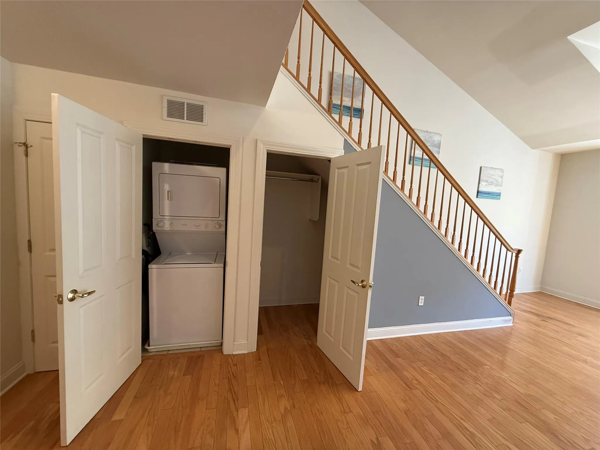 stacked washer and dryer, light wood-style flooring, and visible vents stacked washer and dryer, light wood-style flooring, and visible vents