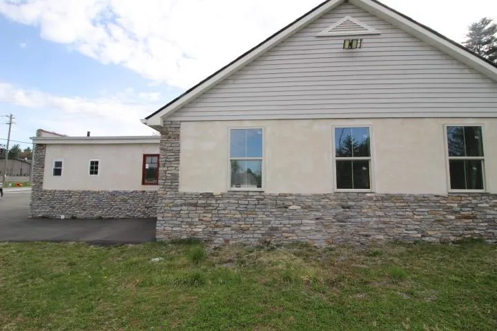 View of home's exterior featuring stucco siding, a yard, and stone siding View of home's exterior featuring stucco siding, a yard, and stone siding