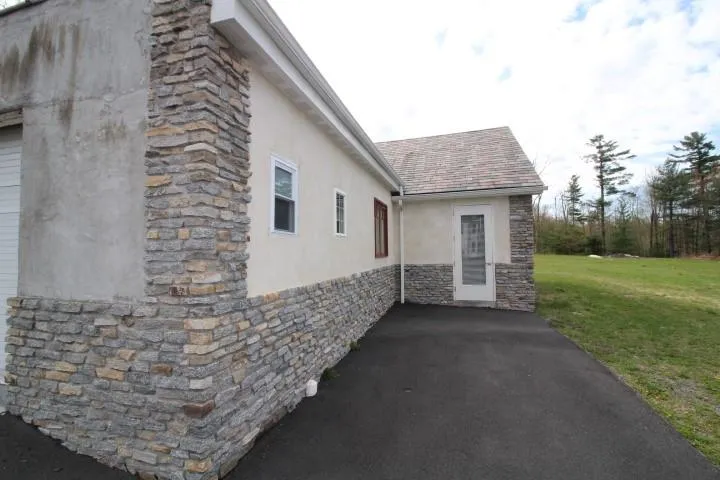 View of home's exterior with a lawn, stucco siding, a shingled roof, and stone siding View of home's exterior with a lawn, stucco siding, a shingled roof, and stone siding