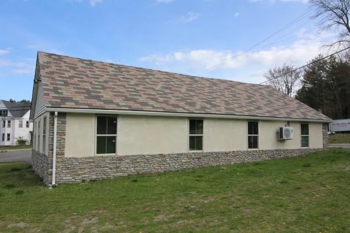 View of home's exterior featuring a lawn, stucco siding, a shingled roof, and stone siding View of home's exterior featuring a lawn, stucco siding, a shingled roof, and stone siding