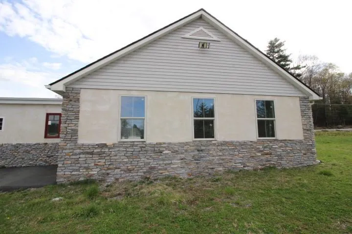 View of home's exterior featuring a lawn, stone siding, and stucco siding View of home's exterior featuring a lawn, stone siding, and stucco siding