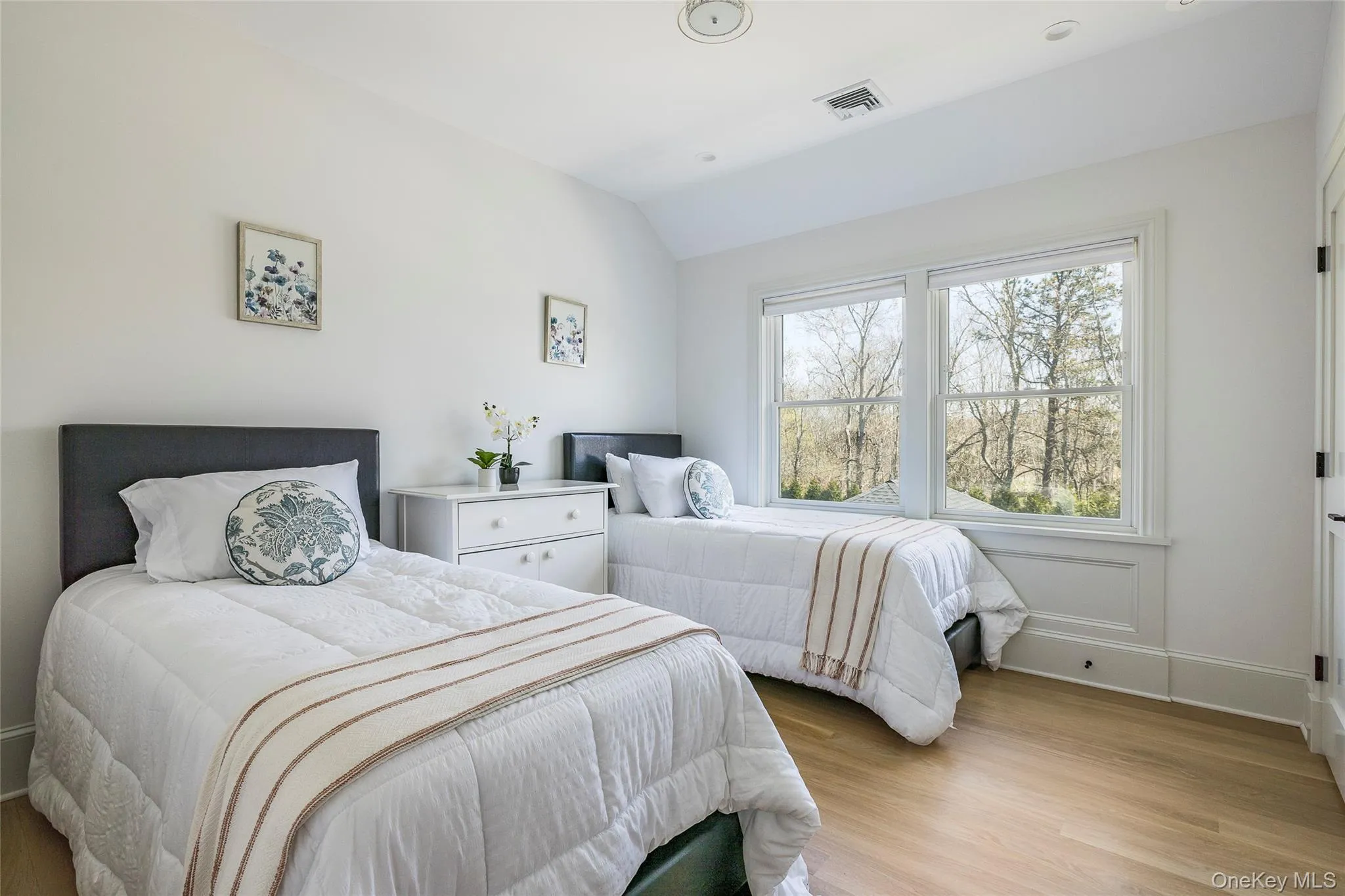 Bedroom featuring baseboards, lofted ceiling, light wood finished floors, and visible vents Bedroom featuring baseboards, lofted ceiling, light wood finished floors, and visible vents