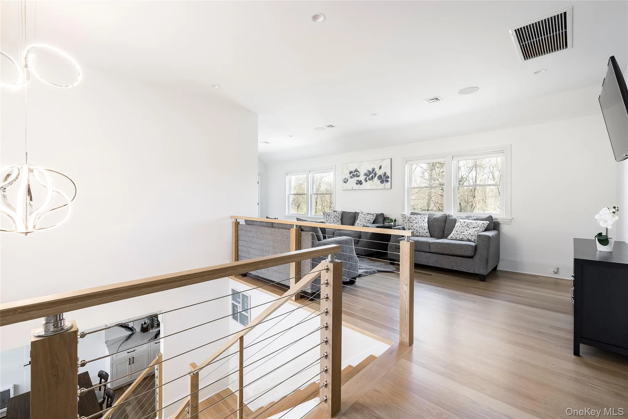 Hall featuring visible vents, wood finished floors, a chandelier, and an upstairs landing Hall featuring visible vents, wood finished floors, a chandelier, and an upstairs landing