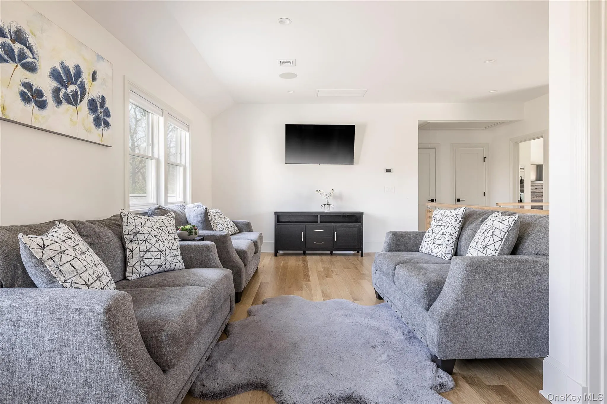Living room with vaulted ceiling and light wood-style flooring Living room with vaulted ceiling and light wood-style flooring