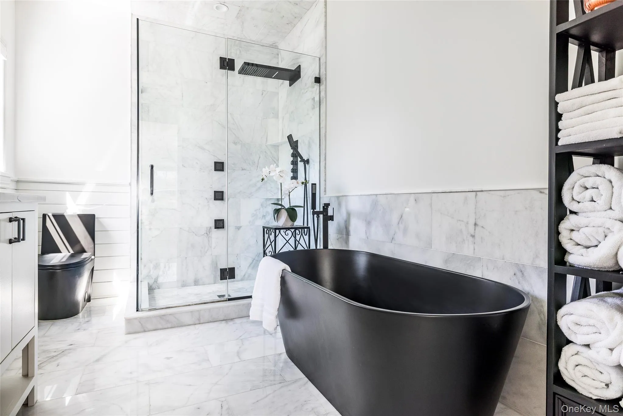Bathroom with a freestanding tub, tile walls, a shower stall, a wainscoted wall, and marble finish floor Bathroom with a freestanding tub, tile walls, a shower stall, a wainscoted wall, and marble finish floor